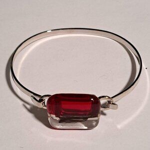 Thin silver tone bracelet with red and clear glass design